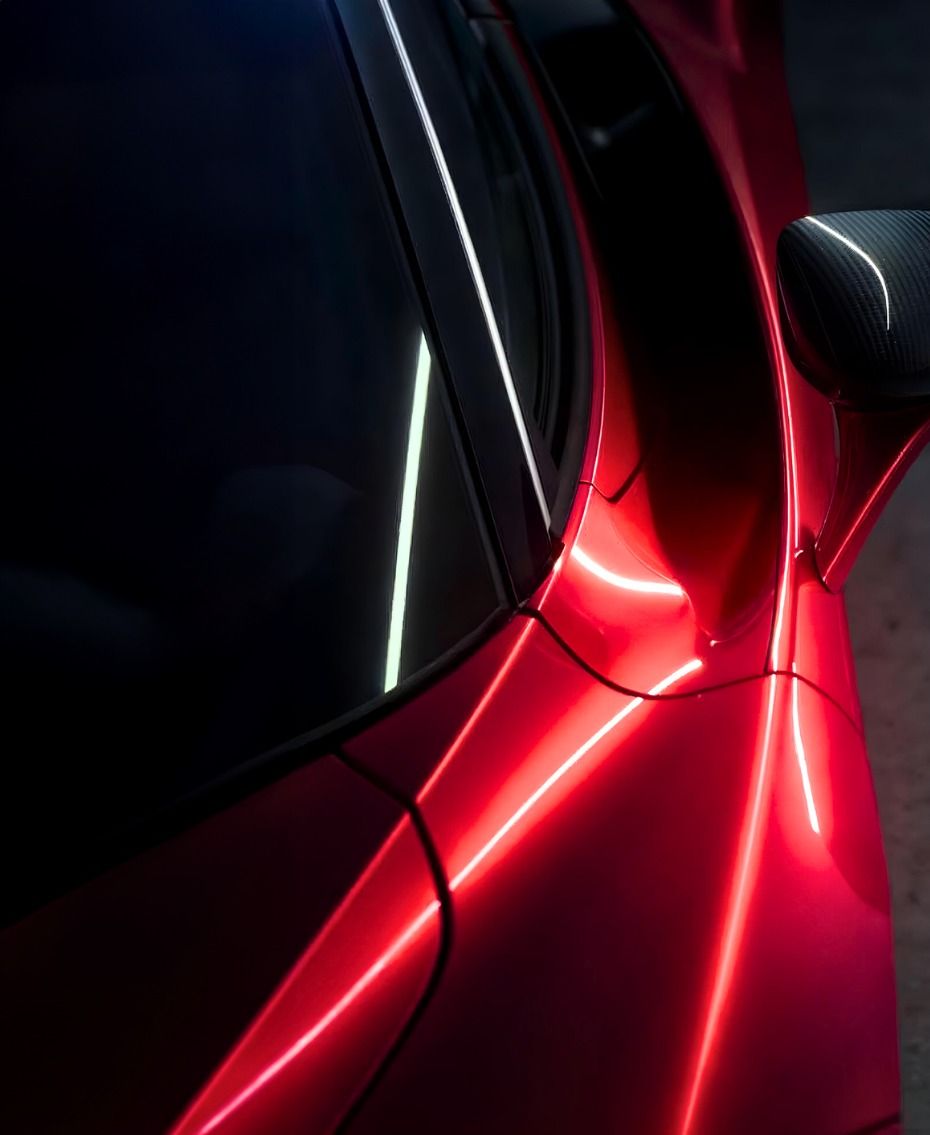 Glossy red supercar door and carbon mirror in low light